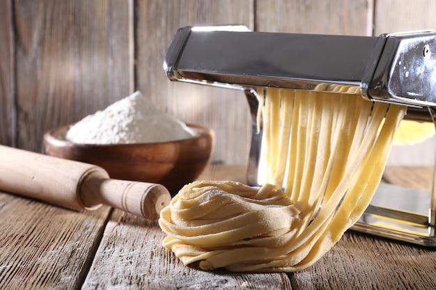 Making noodles with pasta machine on wooden background