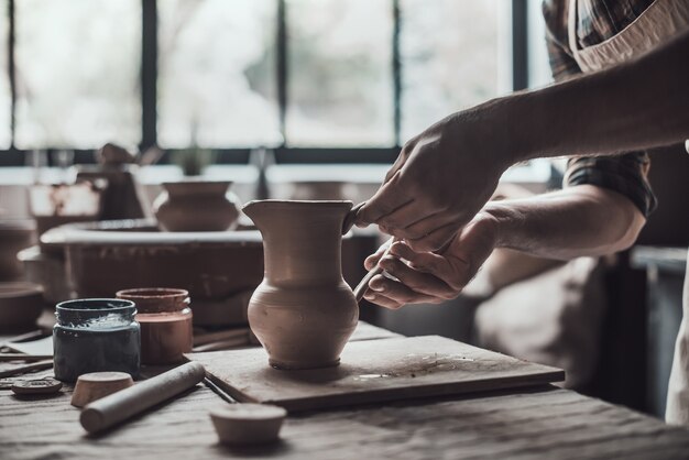 完璧な水差しを作る。彼のワークショップで陶器の水差しを作る陶芸家のクローズアップ