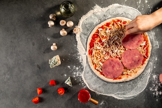 Making a pizza laying out the ham on the dough