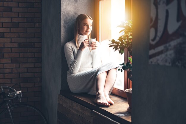 Fare progetti per il nuovo giorno. bella giovane donna che tiene tazza di caffè