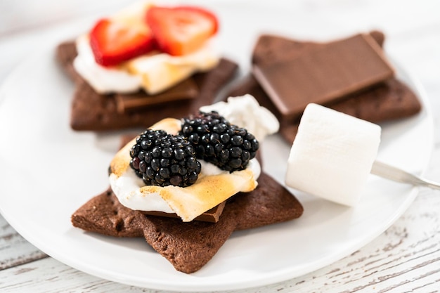 Making s'mores on a homemade star-shaped chocolate graham cracker with toasted marshmallow and fruits.