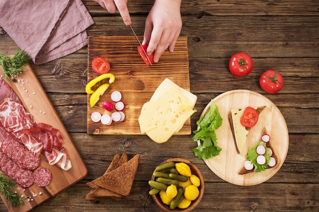 making sandwiches with meat and sausage on wooden table