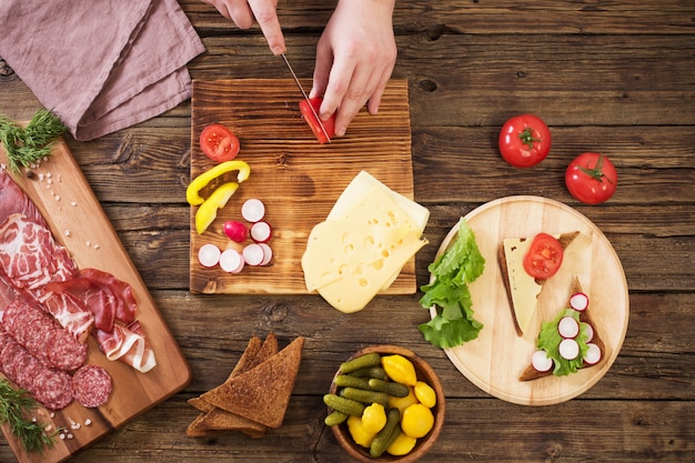 Making sandwiches with meat and sausage on wooden table