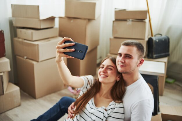 Making a selfie. Cheerful young couple in their new apartment. Conception of moving.