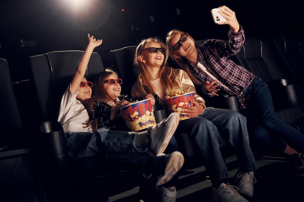 Фото Делая селфи группа детей, сидящих в кинотеатре и вместе смотрящих фильм