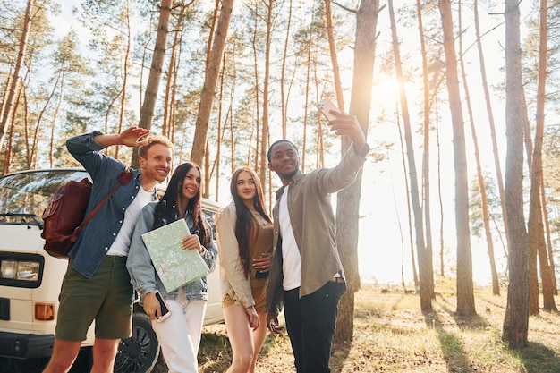 Making selfie group of young people is traveling together in\
the forest at daytime