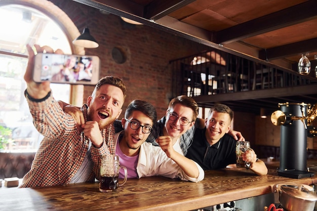 Photo making selfie people in casual clothes sitting in the pub