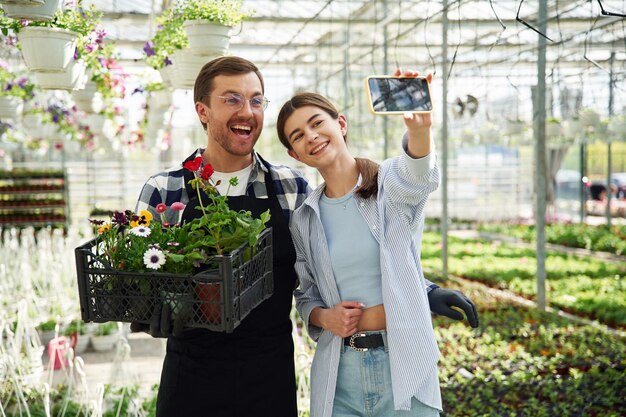 Foto un uomo e una donna fioristi lavorano insieme in una serra luminosa