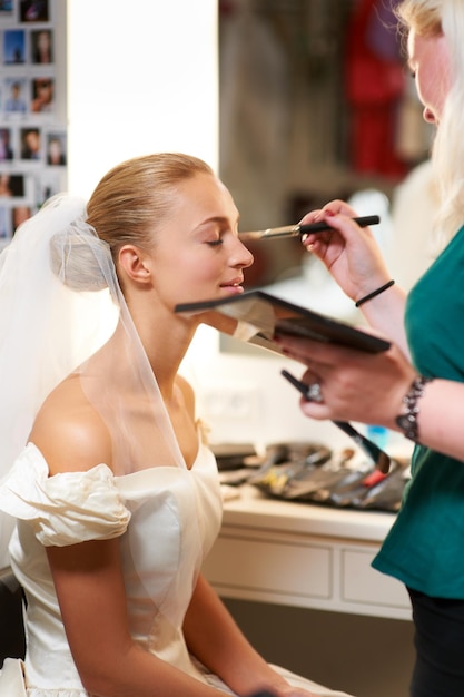 Making sure she looks perfect A makeup artist applying makeup to a bride