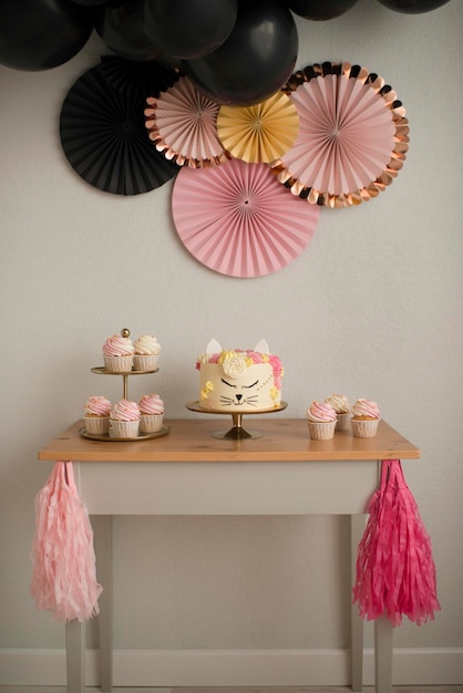 Making a sweet table for a birthday. Cake cat and garland of black balls. Pink and black design.