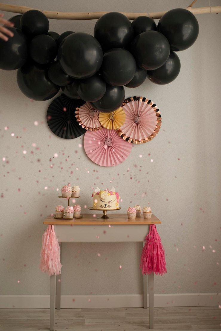 Photo making a sweet table for a birthday. cake cat and garland of black balls. pink and black design.