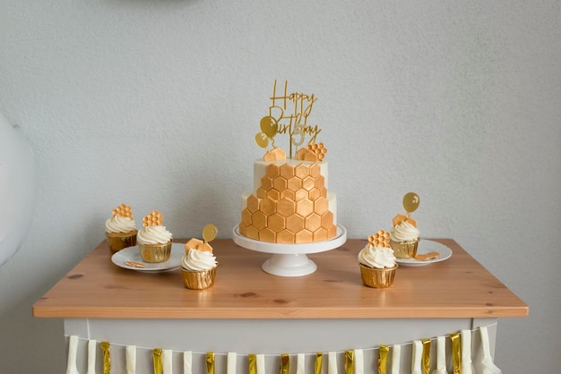 Making a sweet table for a birthday. Cake with honeycombs, golden design.