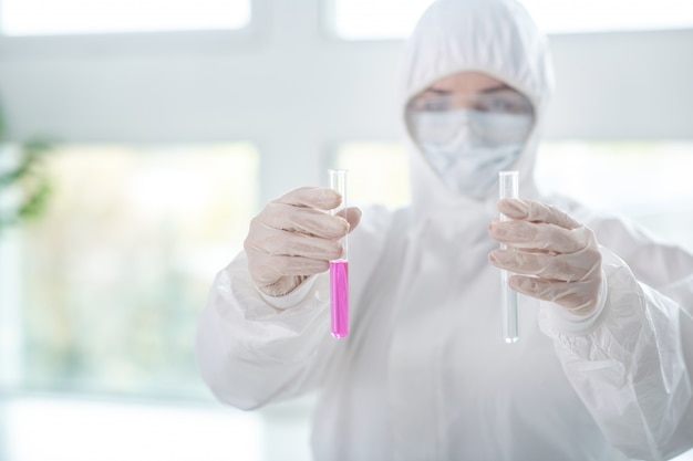 Making a test. Disinfecting worker in protective workwear holding test tubes