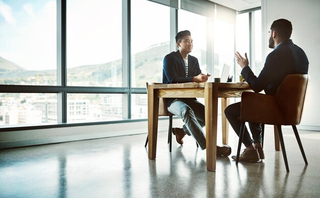 Making that million dollar pitch Shot of two young businessmen having a discussion at a desk in a modern office