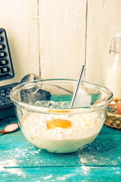 Preparare i waffle a casa - waffle, pastella in una ciotola e ingredienti - latte, uova e farina.