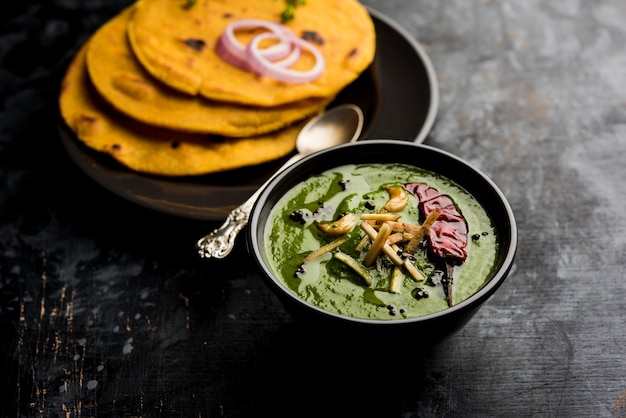 Makki di roti met sarson ka saag, populair punjabi hoofdgerecht recept in de winter gemaakt met maïsbrood mosterdblaadjes curry. geserveerd op humeurige achtergrond. selectieve focus