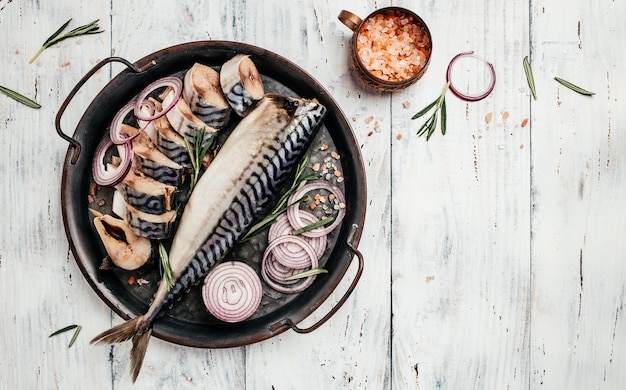 Makreelvissen met zout, ui en kruiden geserveerd op een metalen dienblad. Vis koken. bovenaanzicht