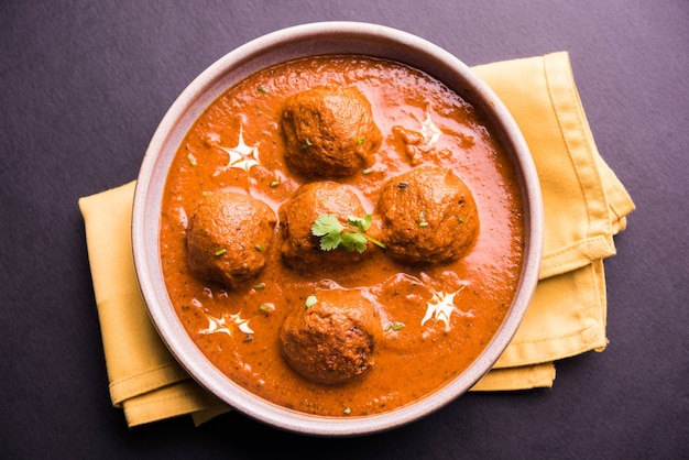 malai kofta curry - classic North Indian dish. vegetarian alternative to meatballs served with tandoori roti or indian bread and green salad, selective focus