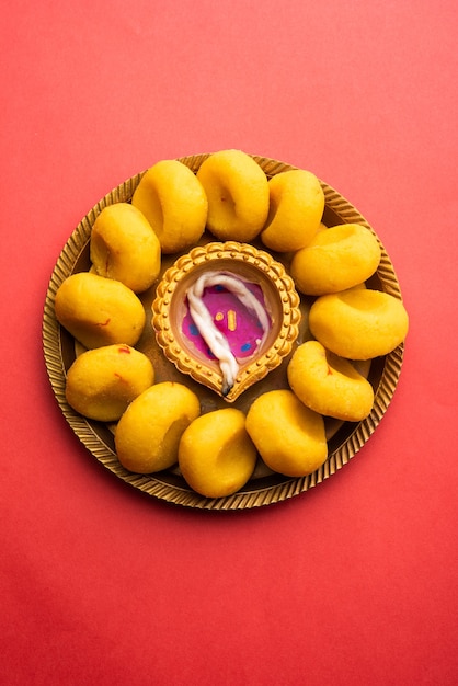 접시에 장식된 Malai Meda 또는 pedha 및 diwali diya 또는 점토 램프 - Happy Diwali Greeting