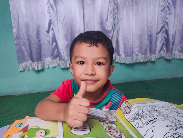 Malaysia Perak 18 November 2021 An Asian boy is reviewing his homework while showing a good gesture