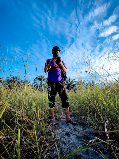 Malaysia perak 28 september 2021 a man is looking at his\
smartphone after taking pictures of the scenery in the area