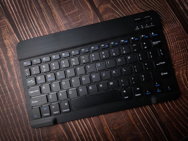 Малайзия 30 апреля 2022 г. Черная беспроводная клавиатура Bluetooth на деревянном фоне