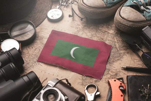 Foto bandiera delle maldive tra gli accessori del viaggiatore sulla vecchia mappa d'annata. concetto di destinazione turistica.