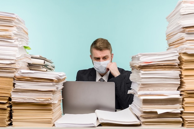 Photo a male accountant or company manager works in an office in a pandemic in view of the accumulated paper work.