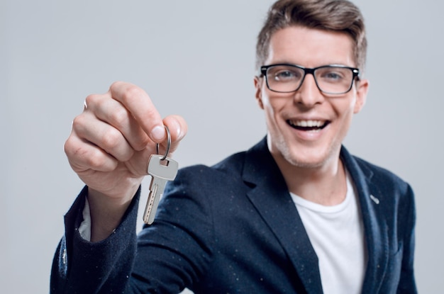 Male adult businessman in a suit giving a keys isolated closeup indoor