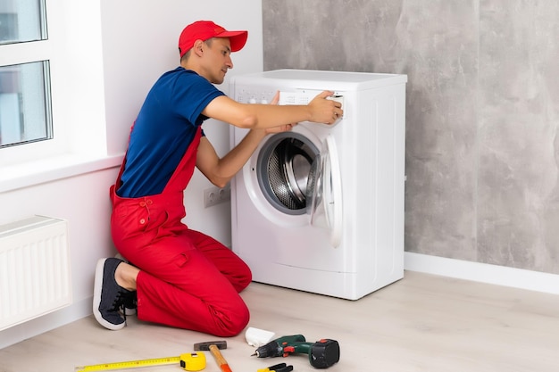 male adult repairman with tool and clipboard checking washing machine in bathroom