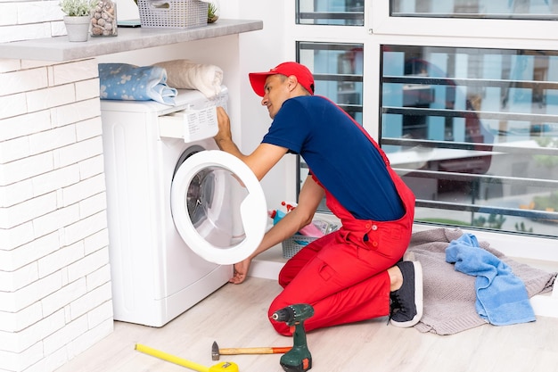 male adult repairman with tool and clipboard checking washing machine in bathroom