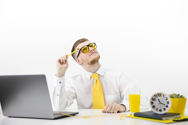 Male adult with laptop looks up thoughtfully, accent on yellow tie juice pot