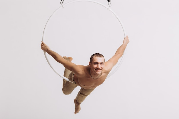 Male aerial gymnast performs acrobatic element in the ring 