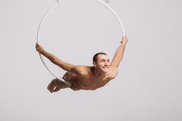 Male aerial gymnast performs acrobatic element in the ring 