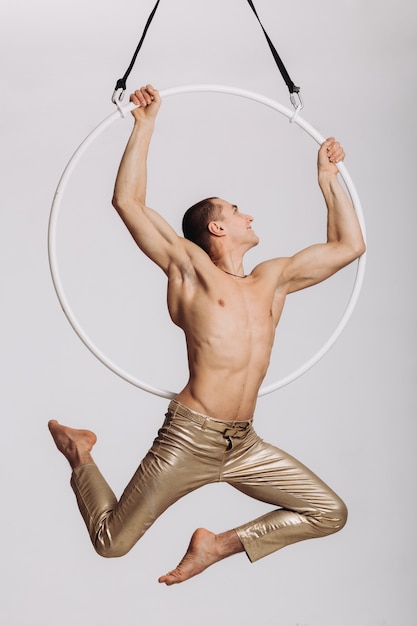 Male aerial gymnast performs acrobatic element in the ring 