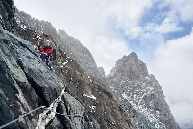 Male alpinist climbing high rocky mountain