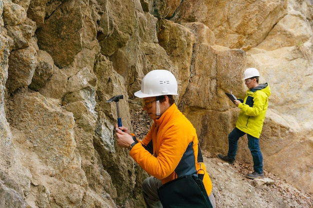 Фото Мужчины и женщины-геологи берут образец минерала и записывают данные в каньоне.