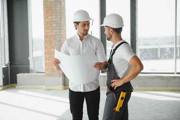 Male Architect Giving Instructions To His Foreman At Construction Site