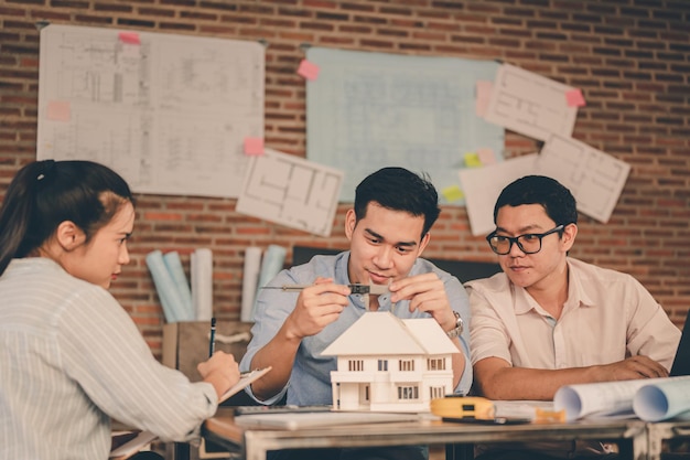 Male architect hands measuring and making model house with them
team on the desk at sunset. engineer, engineering, architecture,
design, planning, occupation concept.