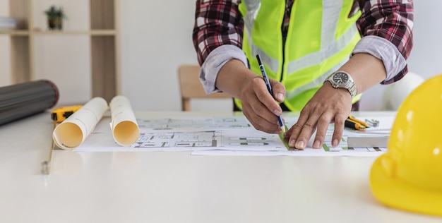 L'architetto maschio sta disegnando sui progetti della casa, sta controllando i piani della casa che ha progettato prima di inviarli ai clienti, sta progettando la casa e gli interni. idee di design per la casa.