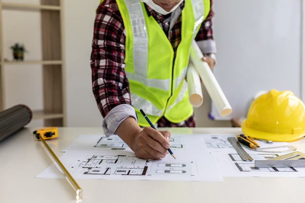 男性建築家は家の設計図に書いています、彼は顧客に送る前に彼が設計した家の計画をチェックしています、彼は家とインテリアを設計しています。ホームデザインのアイデア。