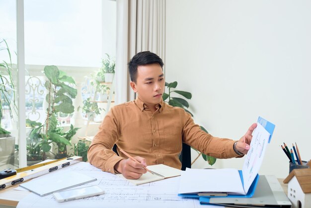 Male architect working with blueprint at his office