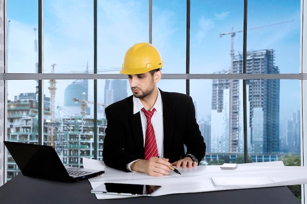 Male architect working with blueprints in the office