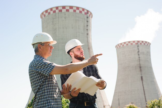 Male architects reviewing documents together at electric power