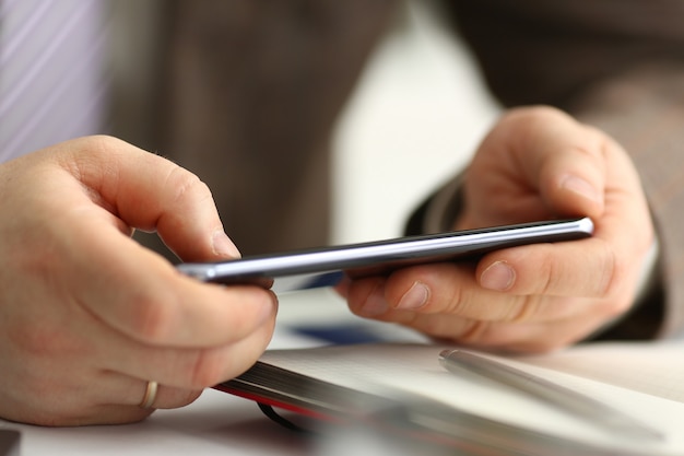 Male arm in suit hold phone and silver pen