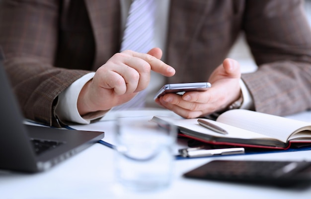 Male arm in suit hold phone and silver pen