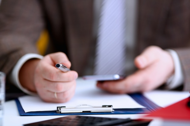 Male arm in suit hold phone and silver pen