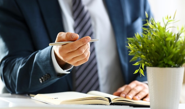 Male arm in suit and tie hold silver pen