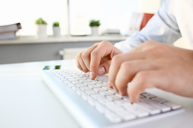 Male arms in suit typing on silver keyboard