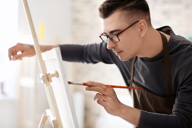 Male artist painting on canvas in workshop